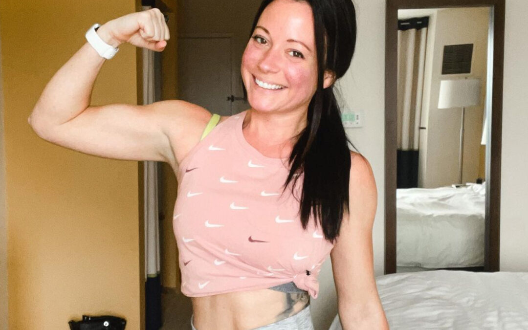 Woman flexing her bicep and smiling before doing a workout