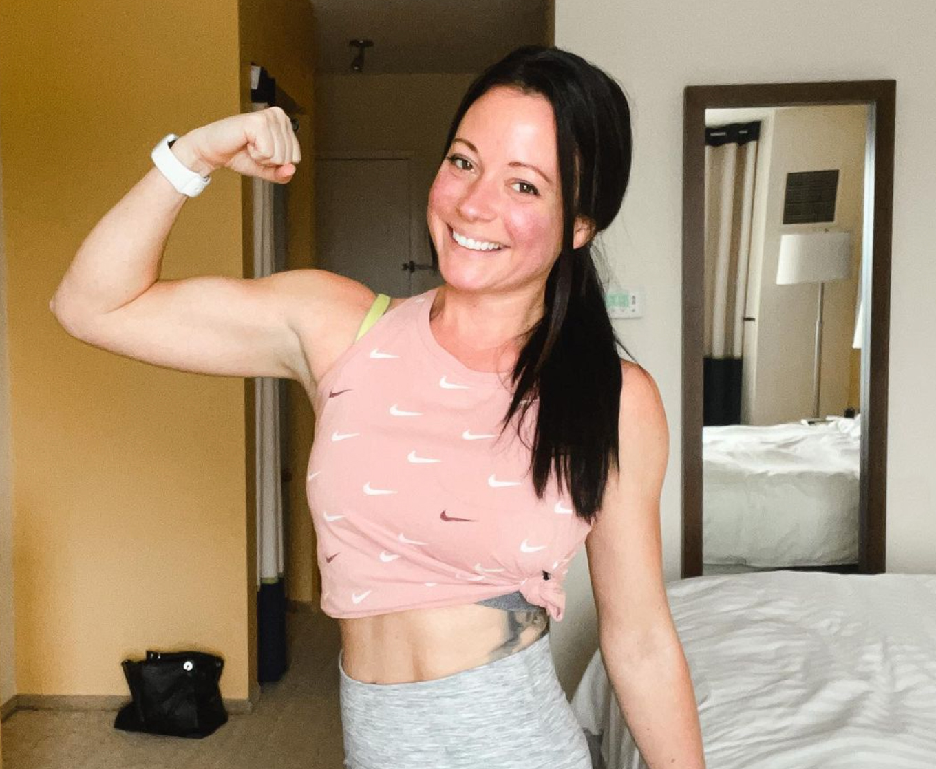 Woman flexing her bicep and smiling before doing a workout